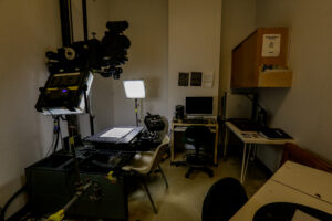 A professional archival or digitization lab featuring a large overhead camera for documents, illuminated by a bright panel, with an adjacent computer workstation.