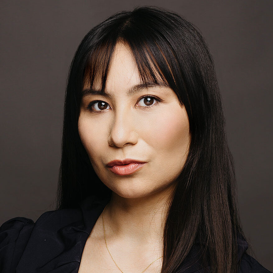 Headshot of a woman with dark hair wearing a gold heart necklace.