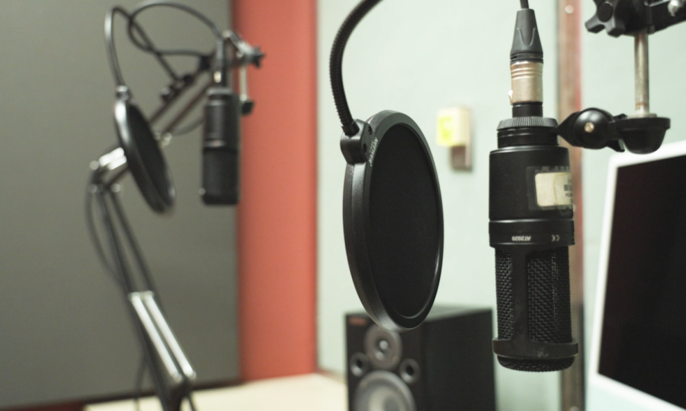 A close-up of a recording studio setup with two microphones and pop filters, ready for audio capture.